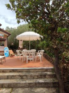 un patio con mesa, sillas y sombrilla en Villetta Cala D'Ambra en San Teodoro