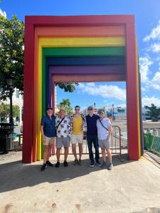un grupo de personas de pie bajo un arco iris en Coqui del Mar - LGBTQ Hotel - Adults Only, en San Juan