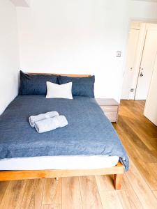 a bed with a blue blanket and two towels on it at Lovely 2 bedroom flat with free parking, great transport links to Central London, the Excel Centre, Canary Wharf and the O2! in London