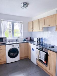 uma cozinha com uma máquina de lavar louça e uma máquina de lavar roupa em Lovely 2 bedroom flat with free parking, great transport links to Central London, the Excel Centre, Canary Wharf and the O2! em Londres