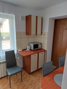 a small kitchen with a microwave and a table and chairs at Apartament Muszelka in Puck +4 photos