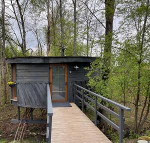 een kleine hut in het bos met een houten loopbrug bij Round house in Sigulda