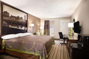 Habitación de hotel con cama, escritorio y TV. en Super 8 by Wyndham Jackson en Jackson