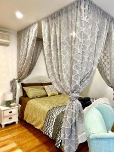 1 dormitorio con 1 cama con cortinas y silla en Mountain Cottage in Dandenong Ranges, en Mount Dandenong