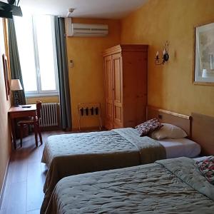 1 dormitorio con 2 camas, vestidor y ventana en Hôtel Saint Jean, en Orange