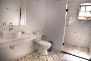 a bathroom with a toilet and a sink and a shower at Pousada Flor de Penedo in Penedo