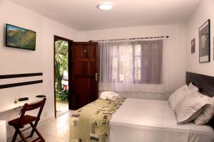 a bedroom with a bed and a desk and a window at Pousada Flor de Penedo in Penedo