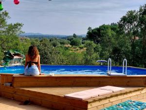 a woman sitting on a deck next to a swimming pool at Quinta da Choupana in Tomar