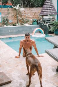 un hombre y un perro parados junto a una piscina en Coqui del Mar - LGBTQ Hotel - Adults Only, en San Juan
