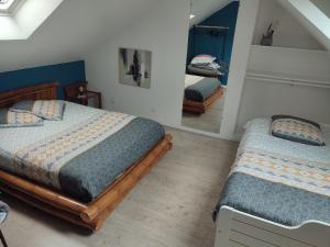 a bedroom with two beds and a mirror at Claude et Astrid in Tour-en-Bessin