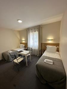 レ・ゼイジー・ド・タヤックにあるHôtel des Roches - Climatisationのベッド2台とテーブルが備わるホテルルームです。