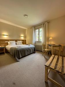 1 dormitorio con cama, escritorio y mesa en Hôtel des Roches - Climatisation, en Les Eyzies-de-Tayac