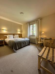 a bedroom with a bed and a desk and a table at Hôtel des Roches - Climatisation in Les Eyzies-de-Tayac