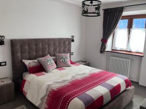 1 dormitorio con 1 cama grande con manta roja y blanca en Dolomites Holiday Home en Canazei