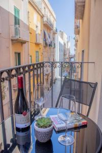 una mesa con una botella de vino y copas en el balcón en Porta delle Botteghelle, en Trapani