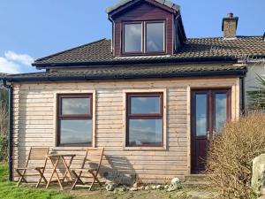 a wooden cabin with two chairs and a table at Rock Cottage in Ardentinny