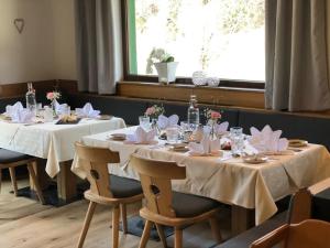 ein Esszimmer mit 2 Tischen und weißen Tischdecken in der Unterkunft Hotel Gasthof Krahlehenhof in Filzmoos