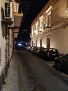 uma rua da cidade à noite com carros estacionados ao lado de edifícios em Robert holiday apartment em Catânia