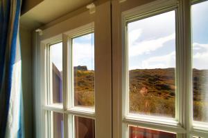 a window with a view of a hill through it at Apartmenthaus Budersandstraße 53 in Hörnum