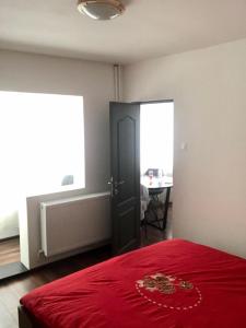 a bedroom with a red bed and a table and window at Silene Studio in Craiova