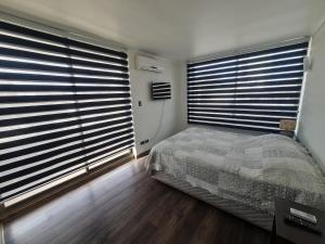 a bedroom with two large windows and a bed at Apartamento Los Andes in Los Andes