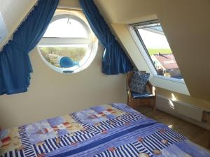 a bedroom with a bed and two windows at Ferienwohnung Inselblick Norddeich mit Meerblick in Norden +16 photos