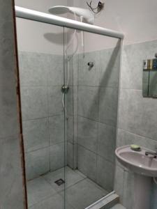 a shower with a glass door next to a sink at Recanto do Parque in Campo Grande