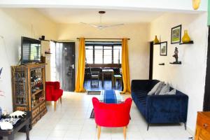 a living room with a blue couch and red chairs at Mavericks Convenient Cozy Loft in Diani's CBD in Ukunda