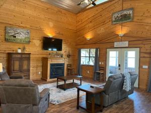 un soggiorno con divano, TV e camino di Strawberry River Ranch Cabin On 700 Acre Ranch a Horseshoe Bend