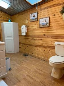 bagno con servizi igienici e parete in legno di Strawberry River Ranch Cabin On 700 Acre Ranch a Horseshoe Bend