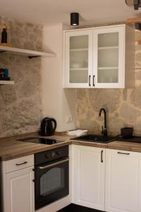a kitchen with white cabinets and a black oven at Stone house Marinko - Free Beach Parking in Tučepi