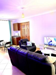 een woonkamer met een bank en een tv bij Elvina Home Buziga in Kampala
