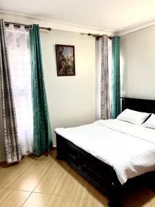 a bedroom with a large bed with green curtains at Elvina Home Buziga in Kampala