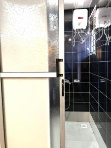 een douche met een glazen deur in de badkamer bij Elvina Home Buziga in Kampala