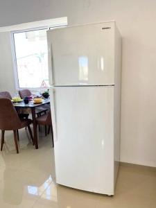 a white refrigerator in a kitchen with a table at Chic apartments next to the sea in Qiryat Yam
