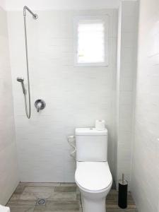 a white bathroom with a toilet and a window at Chic apartments next to the sea in Qiryat Yam