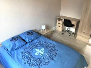 a bedroom with a blue bed with a desk and a chair at Appartement 3 pièces pleins de charmes (Virginie) in Montbéliard
