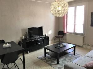 a living room with a couch and a table and a chandelier at Appartement 3 pièces pleins de charmes (Virginie) in Montbéliard