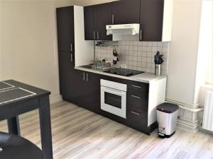 a kitchen with black cabinets and a white stove top oven at Appartement 3 pièces pleins de charmes (Virginie) in Montbéliard +7 photos