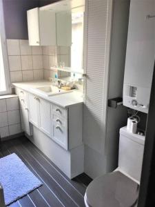 a white bathroom with a sink and a toilet at Appartement 3 pièces pleins de charmes (Virginie) in Montbéliard