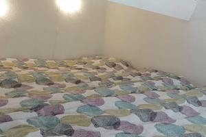 ein Bett mit einer Decke mit Steinen drauf in der Unterkunft la Casa del Sol -2 à 5 pers - 5km de Saint Tropez in Gassin
