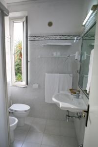 La salle de bains blanche est pourvue de toilettes et d'un lavabo. dans l'établissement Hotel Giardino, à Follonica