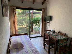 1 dormitorio con cama, mesa y TV en Casa Picaflor UY en Jaureguiberry