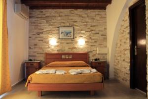 sypialnia z łóżkiem i ceglaną ścianą w obiekcie Naxos Holidays w mieście Naksos