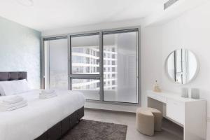 a white bedroom with a large bed and a mirror at Tel Aviv Vacation Apartments in Tel Aviv