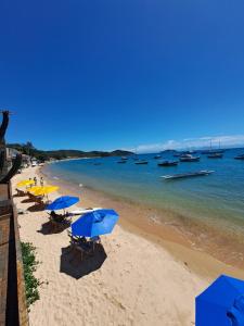 plaża z niebieskimi parasolami i łodziami w wodzie w obiekcie La Coloniale w mieście Búzios
