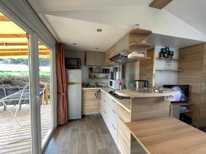 a kitchen with wooden cabinets and a large window at Mobil-home Clim, Tv, Lv - Camping Lac des Rêves 4 étoiles - 010 in Lattes
