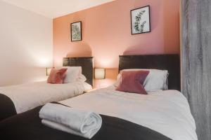 2 camas en una habitación con paredes de color naranja en City Living Penthouse Apartment with Parking (Manchester) en Mánchester