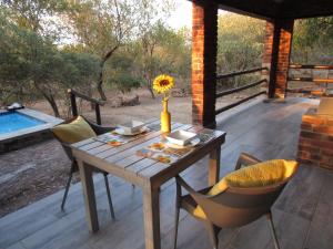 a table and chairs on a patio with a pool at Villa de Leeu, Perfect for Two in Marloth Park