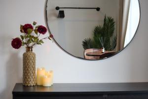 un jarrón con flores y velas sobre una mesa con un espejo en Berry's Loft - Central Location and Fast WIFI, en Knaresborough